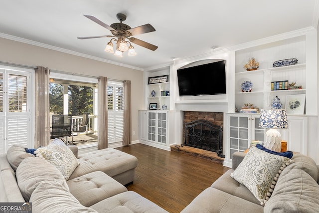 living area featuring crown molding, ceiling fan, a fireplace, wood finished floors, and built in shelves
