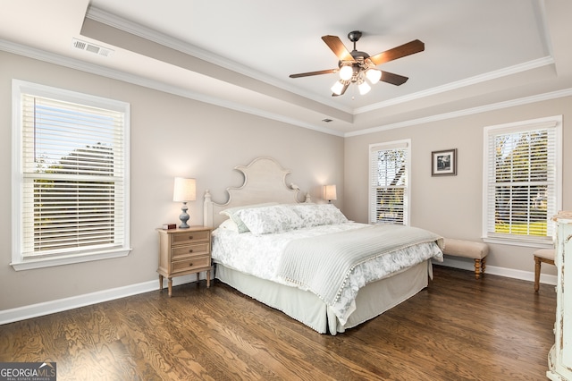 bedroom featuring ornamental molding, visible vents, a tray ceiling, and dark wood-style floors