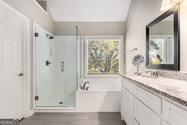 full bathroom with a stall shower, a garden tub, lofted ceiling, and vanity