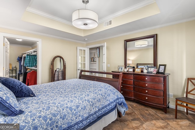 bedroom with ornamental molding, a closet, a raised ceiling, and a spacious closet