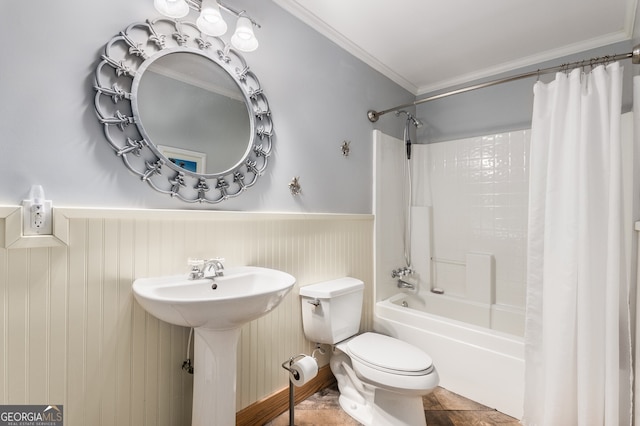 bathroom with wainscoting, toilet, a sink, shower / tub combo with curtain, and crown molding