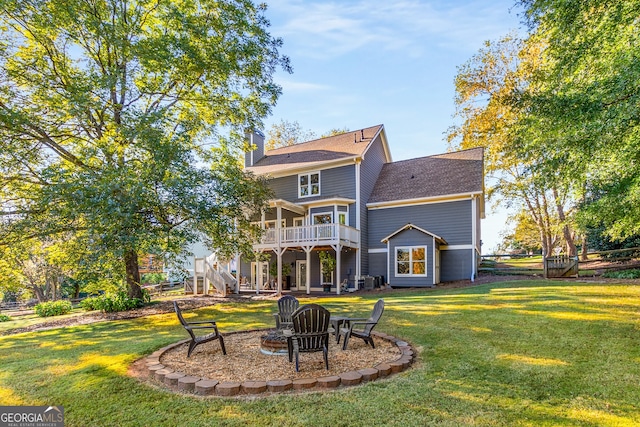 back of house featuring a yard, stairway, a fire pit, and a chimney