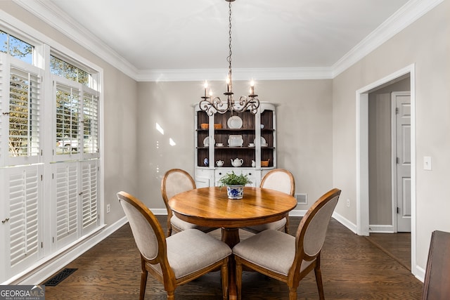 dining room featuring dark wood finished floors, ornamental molding, baseboards, visible vents, and a notable chandelier