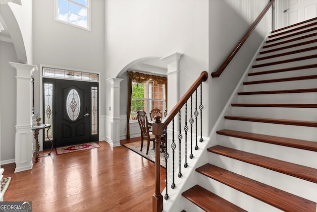 entryway featuring wood finished floors, arched walkways, a high ceiling, and a healthy amount of sunlight