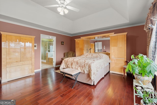 bedroom with baseboards, ensuite bathroom, wood finished floors, and a raised ceiling