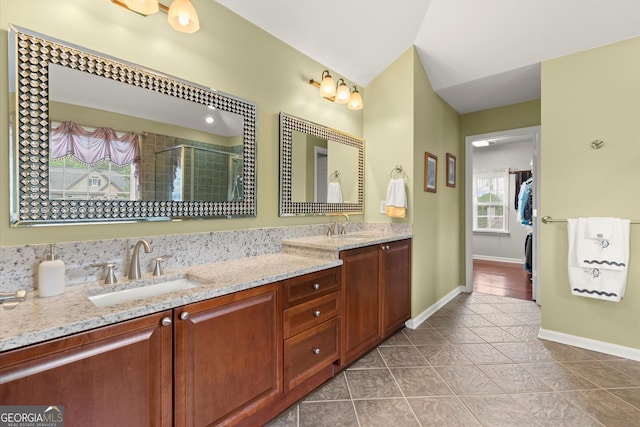 bathroom with double vanity, baseboards, tile patterned floors, a shower stall, and a sink