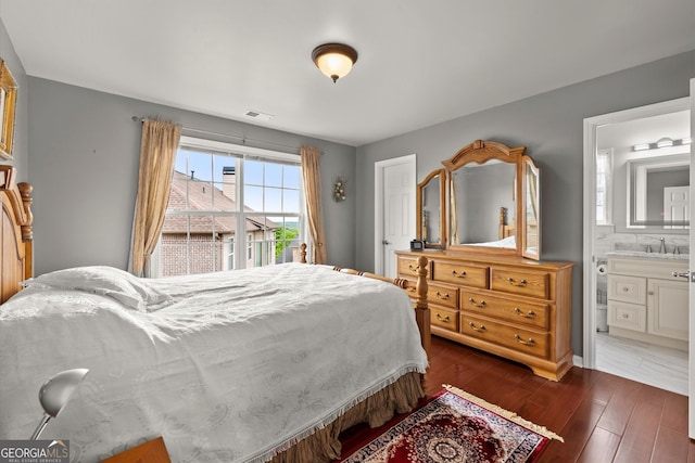 bedroom with visible vents, a sink, connected bathroom, and dark wood-type flooring