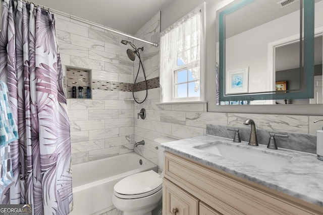full bathroom featuring vanity, toilet, tile walls, backsplash, and shower / tub combo