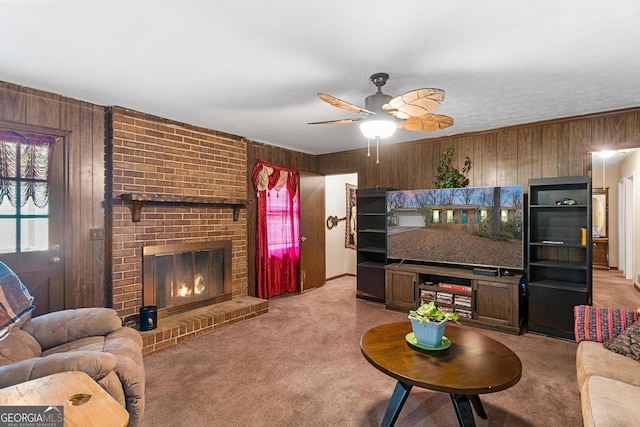 living area with wooden walls, ceiling fan, light carpet, and a fireplace
