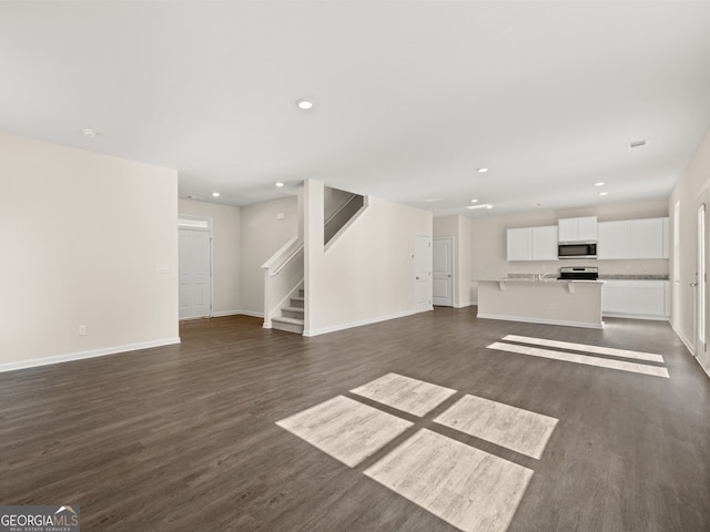 8230 Coldstream Dr, Fairburn, GA 30213 - unfurnished living room featuring dark wood-type flooring, stairs, and recessed lighting