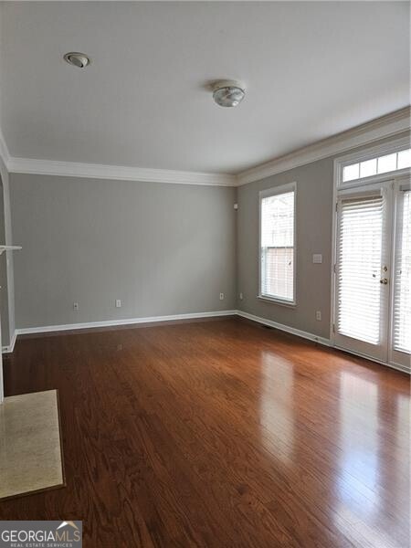 unfurnished living room with baseboards, ornamental molding, french doors, and wood finished floors