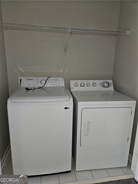 clothes washing area featuring light tile patterned flooring, laundry area, and washing machine and dryer