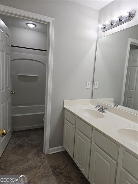 full bath featuring a sink, shower / bathtub combination, baseboards, and double vanity