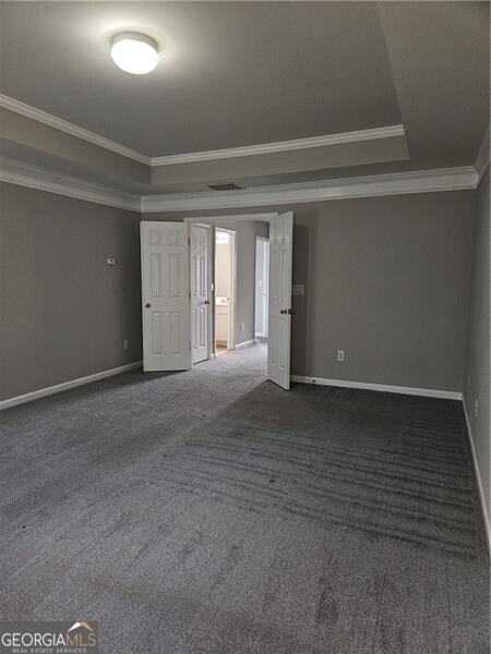 spare room with baseboards, ornamental molding, carpet, and a tray ceiling
