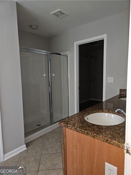 full bath featuring visible vents, double vanity, tile patterned floors, a sink, and a stall shower