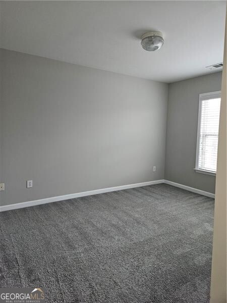 unfurnished room with carpet floors, baseboards, and visible vents