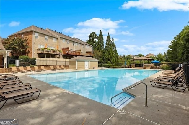 community pool featuring fence, a patio, a storage unit, a gazebo, and an outbuilding