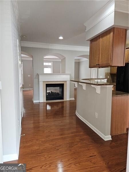 kitchen featuring baseboards, brown cabinetry, crown molding, and a breakfast bar area