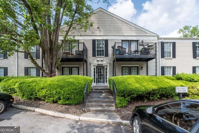 view of property featuring a balcony and uncovered parking