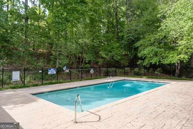 community pool with fence and a patio area