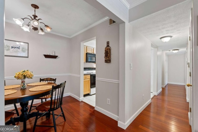 dining area with an inviting chandelier, dark wood-style flooring, visible vents, and crown molding