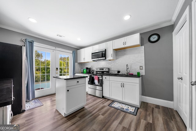 209 Braemar Ct, Mcdonough, GA 30253 - kitchen featuring crown molding, dark countertops, appliances with stainless steel finishes, a center island, and visible vents