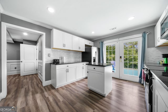 209 Braemar Ct, Mcdonough, GA 30253 - kitchen featuring visible vents, ornamental molding, a center island, black electric range, and stainless steel fridge with ice dispenser