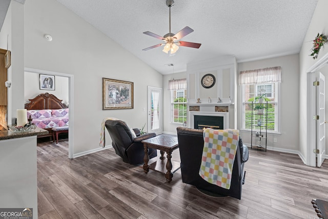 living room with a textured ceiling, a ceiling fan, wood finished floors, and a healthy amount of sunlight