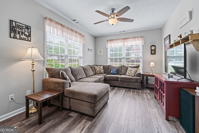 living area with a textured ceiling, wood finished floors, ceiling fan, and visible vents