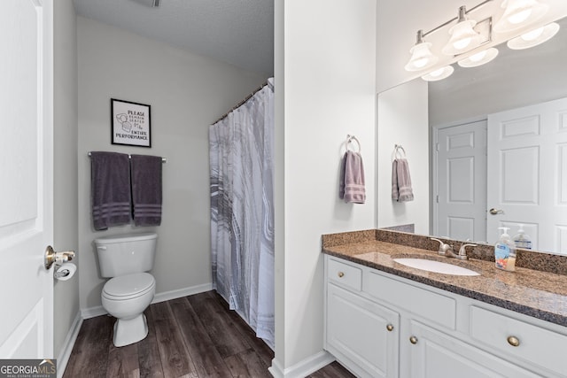 bathroom featuring wood finished floors, toilet, vanity, and baseboards