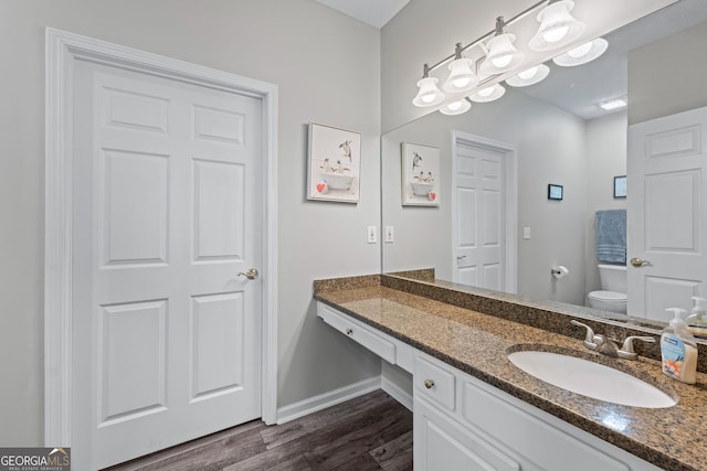 bathroom featuring toilet, vanity, wood finished floors, and baseboards