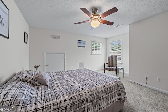 bedroom with carpet flooring, a textured ceiling, visible vents, and baseboards
