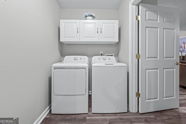 washroom with dark wood-type flooring, cabinet space, a textured ceiling, and washing machine and clothes dryer