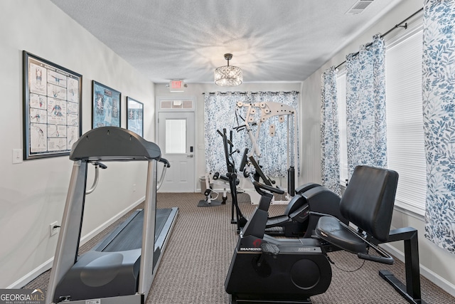 workout area with a textured ceiling, visible vents, carpet floors, an inviting chandelier, and baseboards