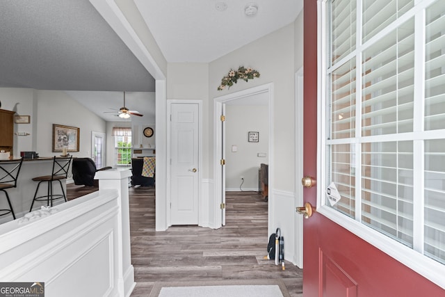 foyer entrance with ceiling fan, vaulted ceiling, and light wood-style floors