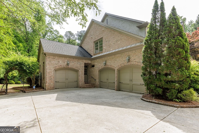 traditional home featuring brick siding, concrete driveway, an attached garage, and roof with shingles