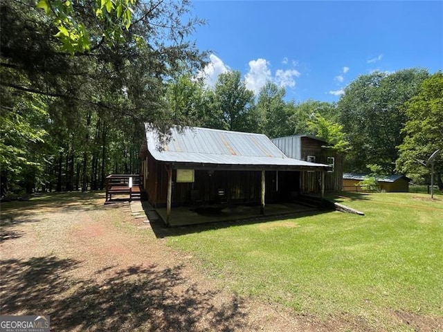 back of property with an outbuilding, a lawn, metal roof, and a storage unit