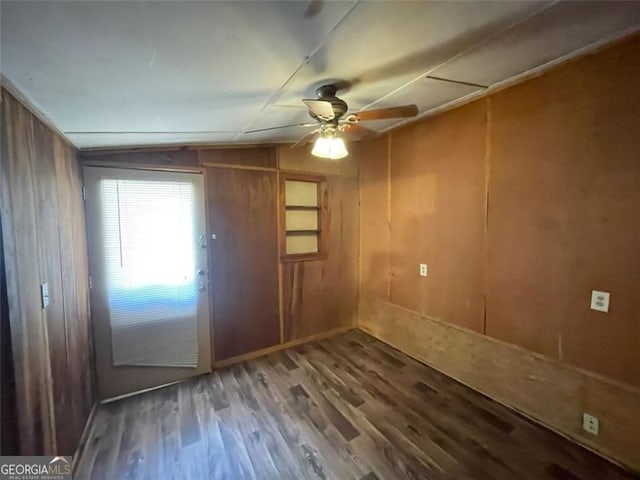 interior space with wooden walls, wood finished floors, and a ceiling fan