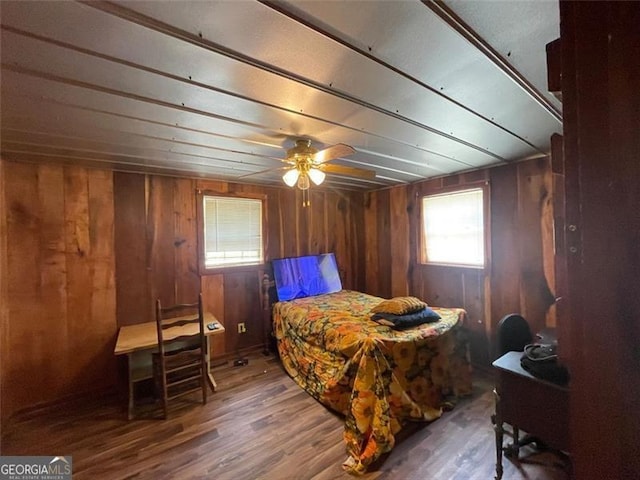 bedroom featuring wood walls, wood finished floors, and a ceiling fan