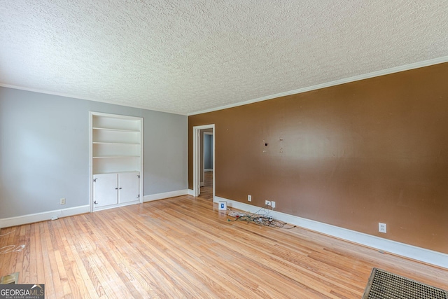 spare room with wood-type flooring, a textured ceiling, built in features, and baseboards