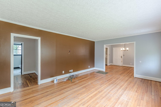 unfurnished room with crown molding, a notable chandelier, light wood-style floors, a textured ceiling, and baseboards