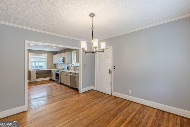 kitchen featuring appliances with stainless steel finishes, light wood-type flooring, light countertops, a sink, and a chandelier