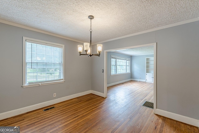 unfurnished dining area with baseboards, wood finished floors, a textured ceiling, and a chandelier