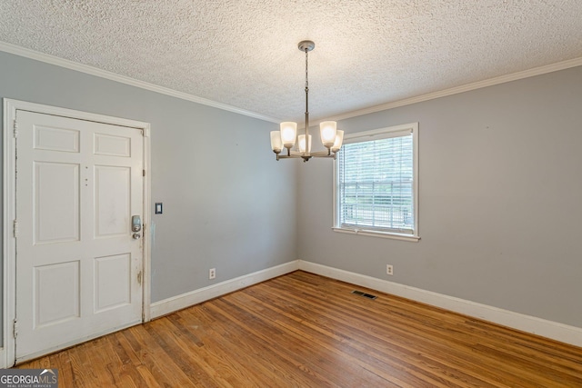 unfurnished dining area with baseboards, a textured ceiling, visible vents, and wood finished floors