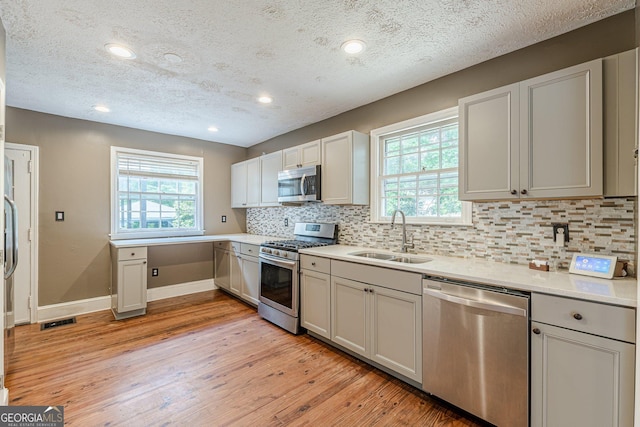 kitchen featuring visible vents, light wood-style floors, baseboards, a sink, and stainless steel appliances