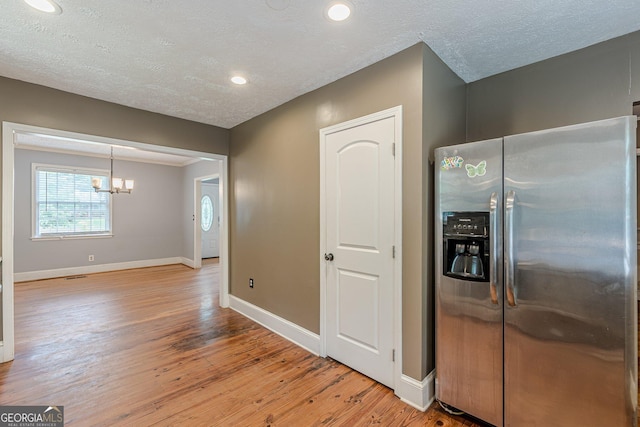 kitchen featuring an inviting chandelier, stainless steel fridge with ice dispenser, a textured ceiling, baseboards, and light wood-type flooring