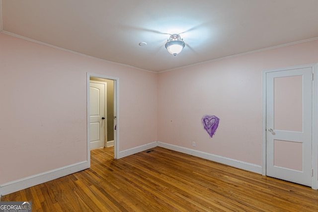 spare room with baseboards, ornamental molding, and wood finished floors