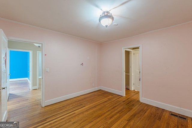 unfurnished room with visible vents, baseboards, crown molding, and light wood-type flooring