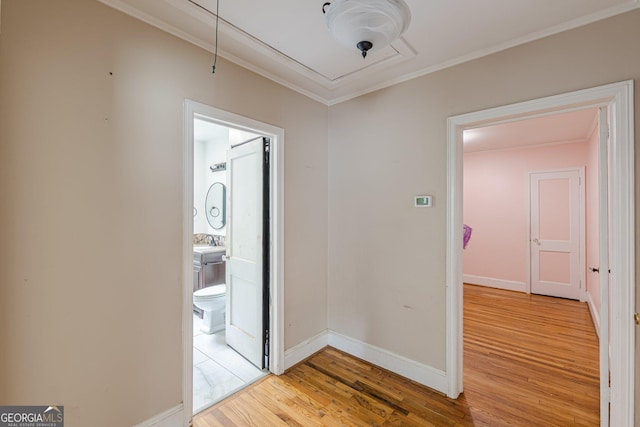 corridor with crown molding, baseboards, attic access, and wood finished floors