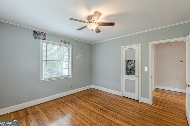 empty room featuring baseboards, crown molding, ceiling fan, and wood finished floors